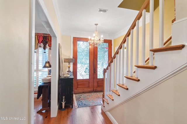 entrance foyer featuring hardwood / wood-style flooring, an inviting chandelier, a wealth of natural light, and crown molding