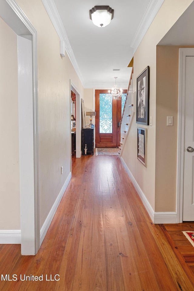 hall featuring hardwood / wood-style floors, ornamental molding, and a notable chandelier