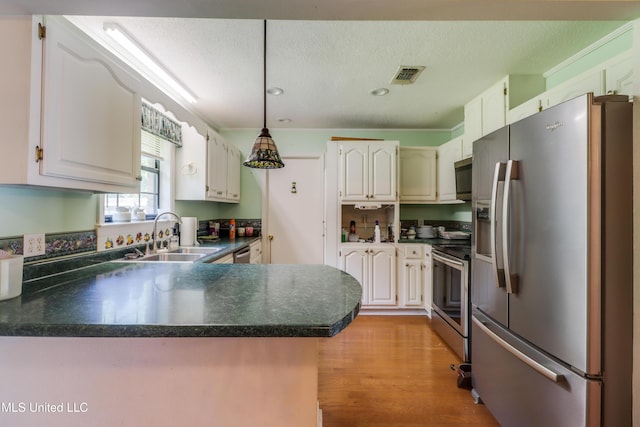 419 Cove Dr, Biloxi, MS 39531 - kitchen with visible vents, a sink, a peninsula, dark countertops, and stainless steel appliances