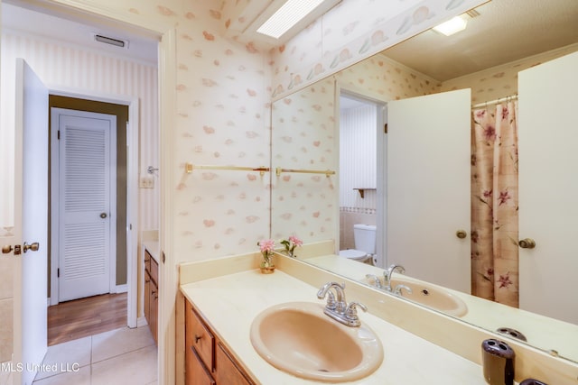 419 Cove Dr, Biloxi, MS 39531 - full bathroom with wallpapered walls, toilet, visible vents, tile patterned floors, and vanity