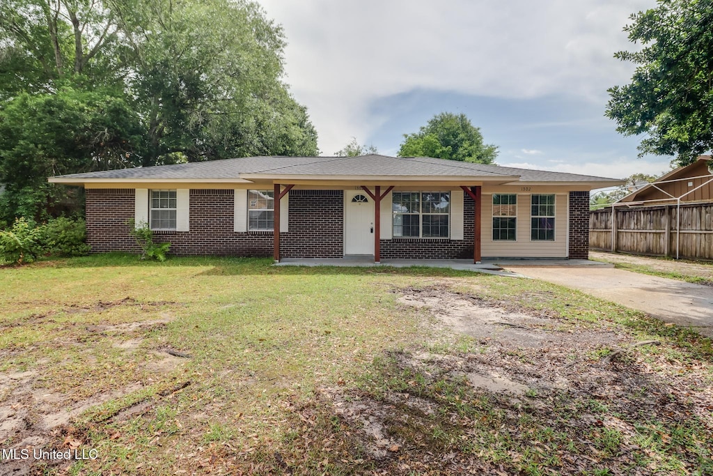 single story home featuring brick siding, fence, and a front yard