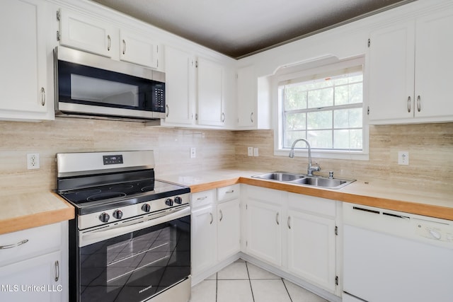 1302 Parktown Dr, Ocean Springs, MS 39564 - kitchen with backsplash, a sink, light tile patterned flooring, stainless steel appliances, and white cabinetry