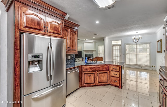 kitchen with tile countertops, appliances with stainless steel finishes, a peninsula, a fireplace, and a sink