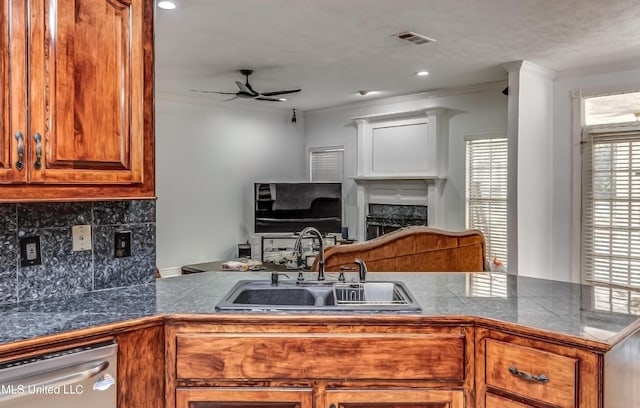 kitchen featuring a fireplace, visible vents, stainless steel dishwasher, brown cabinetry, and a sink