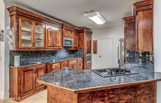 kitchen featuring tile countertops, light tile patterned floors, stainless steel appliances, decorative backsplash, and a peninsula