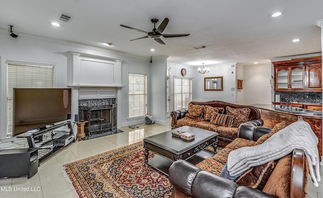 living room with a fireplace, visible vents, crown molding, and light tile patterned flooring