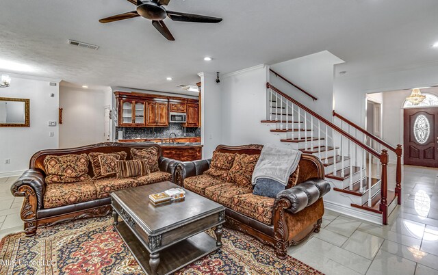 living room with ornamental molding, visible vents, and stairway