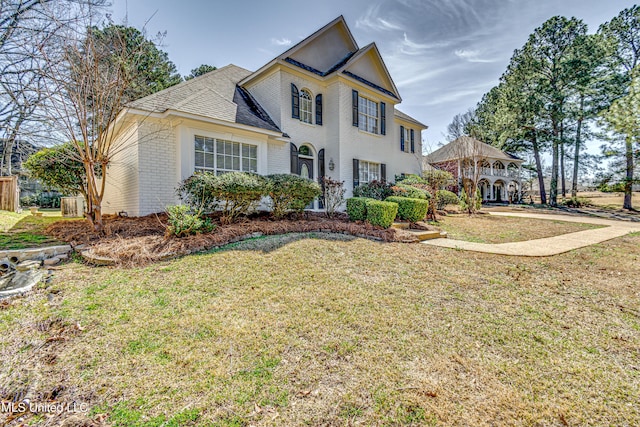 traditional-style home featuring brick siding and a front yard