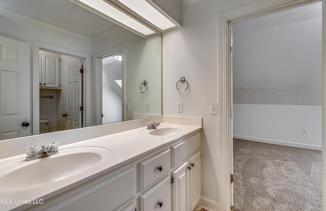 bathroom with double vanity, a sink, toilet, and baseboards