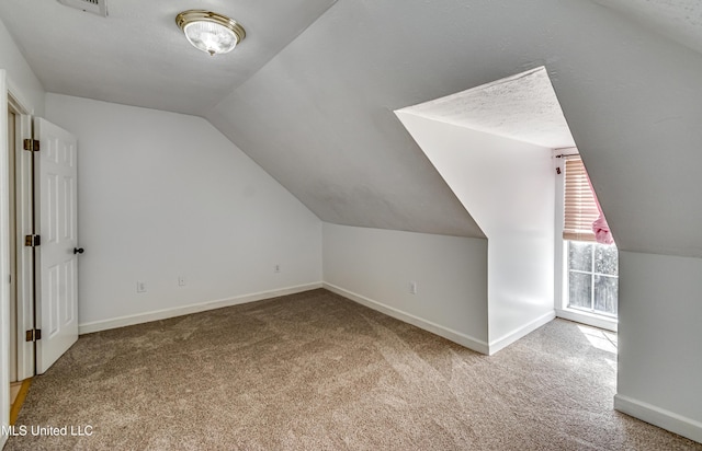 bonus room featuring a textured ceiling, baseboards, vaulted ceiling, and carpet flooring