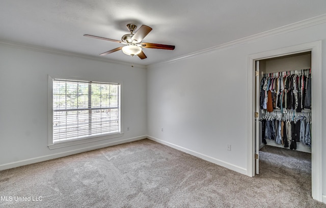 unfurnished bedroom with a spacious closet, baseboards, crown molding, and carpet flooring