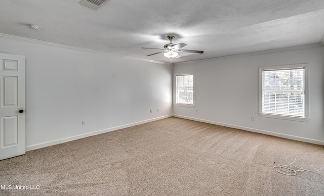 unfurnished room featuring carpet floors, crown molding, visible vents, ceiling fan, and baseboards