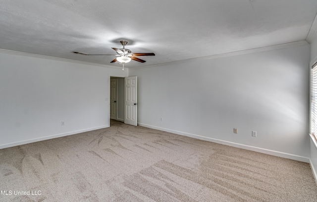 spare room featuring ceiling fan, carpet floors, baseboards, and crown molding