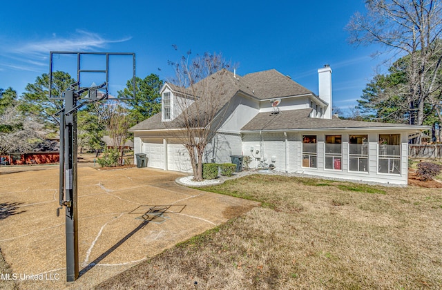 exterior space with a garage, driveway, brick siding, a chimney, and a front yard