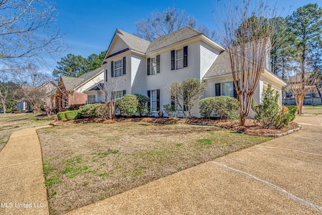 view of front of house featuring a garage, brick siding, a front lawn, and roof with shingles