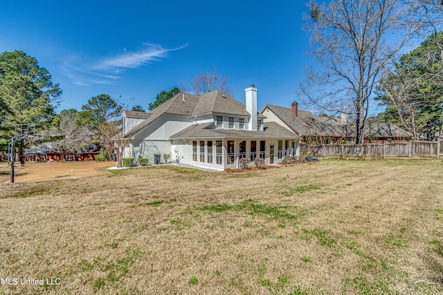 rear view of property with a chimney, fence, and a yard