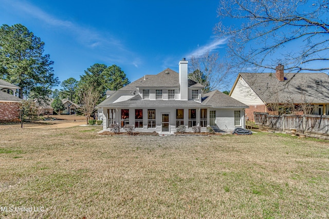 back of house featuring a chimney, fence, and a yard