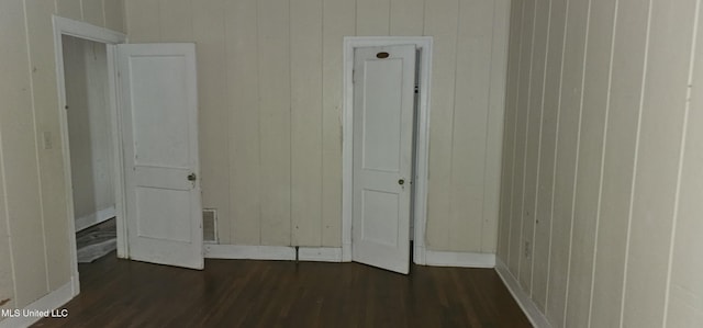 1080 Alta Vista Blvd, Jackson, MS 39209 - unfurnished bedroom featuring dark wood finished floors, baseboards, and wood walls