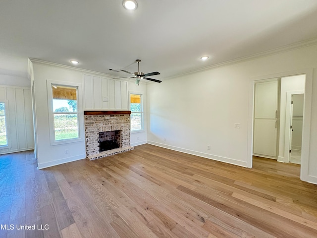 unfurnished living room featuring light hardwood / wood-style flooring, ornamental molding, a fireplace, and ceiling fan