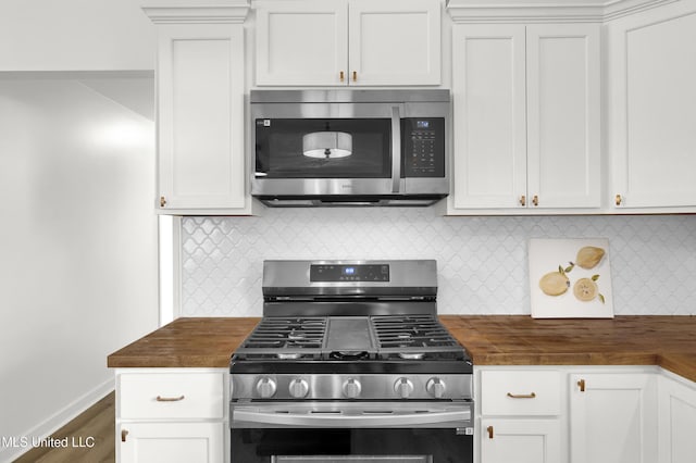 kitchen with white cabinetry, butcher block countertops, and appliances with stainless steel finishes