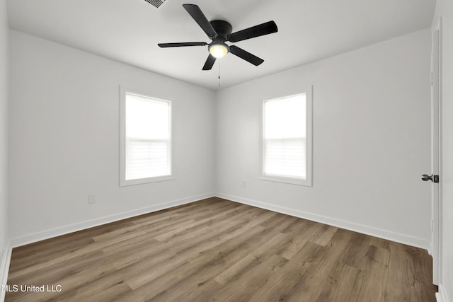 spare room featuring ceiling fan, a healthy amount of sunlight, and light wood-type flooring