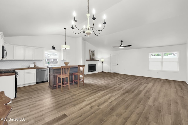 kitchen with vaulted ceiling, appliances with stainless steel finishes, pendant lighting, wood-type flooring, and white cabinets