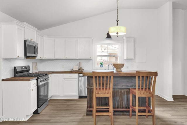 kitchen with white cabinetry, appliances with stainless steel finishes, decorative light fixtures, and wooden counters