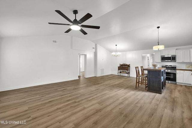 kitchen with ceiling fan with notable chandelier, hardwood / wood-style flooring, stainless steel appliances, and lofted ceiling