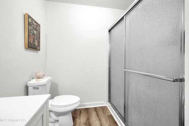 bathroom with wood-type flooring, vanity, toilet, and a shower with door