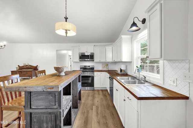 kitchen featuring wood counters, pendant lighting, stainless steel appliances, and sink