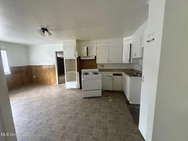 kitchen with white cabinets, sink, wooden walls, range hood, and white gas stove