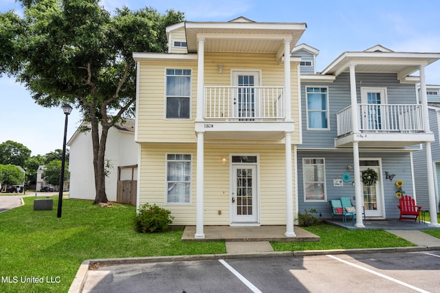 view of property featuring a balcony and a front lawn