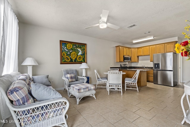 tiled living room with ceiling fan and a textured ceiling