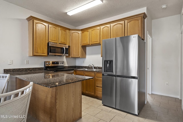 kitchen with kitchen peninsula, appliances with stainless steel finishes, a textured ceiling, dark stone counters, and sink