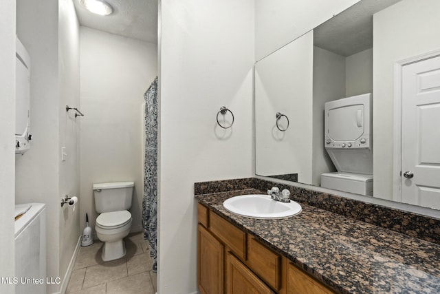 bathroom with tile patterned floors, stacked washer and dryer, toilet, vanity, and a textured ceiling