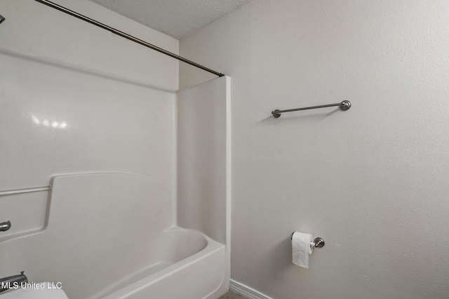 bathroom featuring washtub / shower combination and a textured ceiling