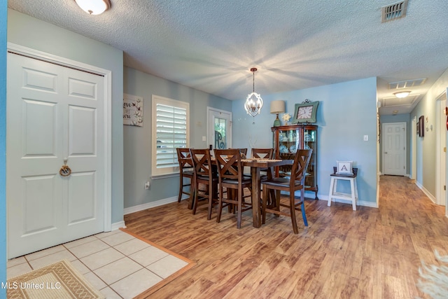 7505 Martin Ct, Ocean Springs, MS 39564 - dining space with light wood-type flooring, a textured ceiling, attic access, baseboards, and a chandelier