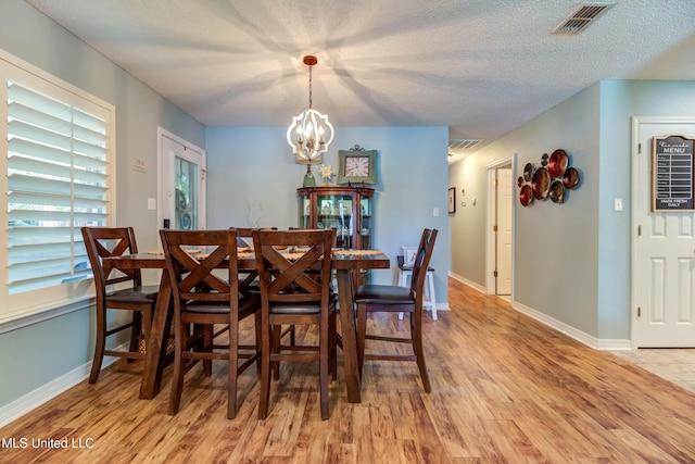 7505 Martin Ct, Ocean Springs, MS 39564 - dining room with light wood-style floors, a chandelier, a textured ceiling, and baseboards