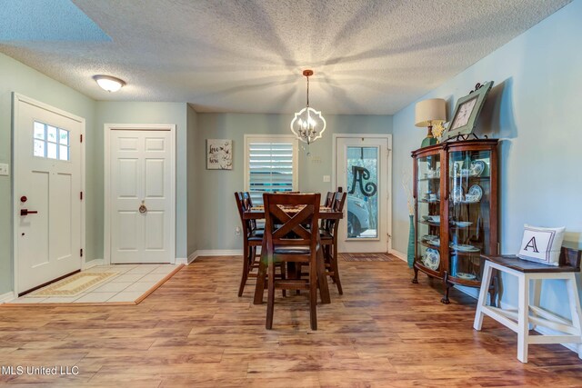 7505 Martin Ct, Ocean Springs, MS 39564 - dining space featuring a chandelier, light wood finished floors, a textured ceiling, and baseboards