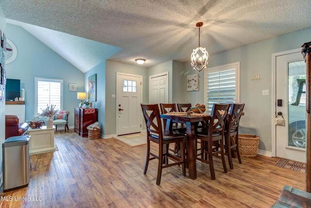 7505 Martin Ct, Ocean Springs, MS 39564 - dining room featuring a chandelier, light wood finished floors, baseboards, a textured ceiling, and lofted ceiling