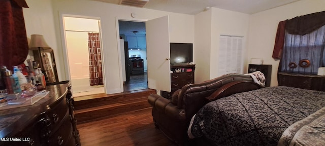 bedroom with ensuite bathroom and dark hardwood / wood-style floors