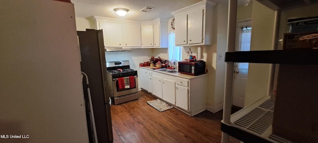 kitchen featuring gas stove, white cabinets, hardwood / wood-style flooring, and a textured ceiling