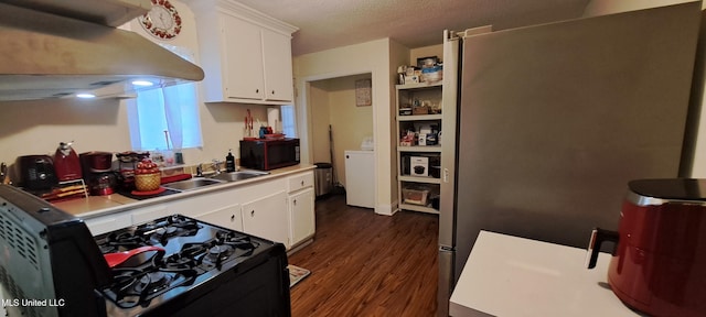 kitchen with washer / dryer, black appliances, sink, white cabinetry, and dark hardwood / wood-style floors