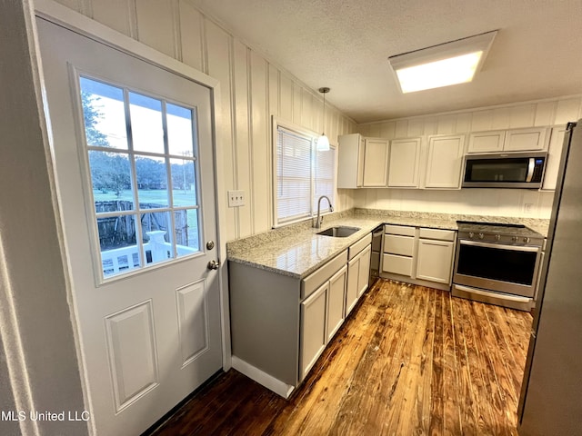 kitchen featuring white cabinetry, hanging light fixtures, dark hardwood / wood-style floors, and appliances with stainless steel finishes