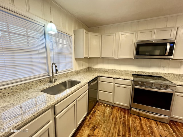 kitchen with pendant lighting, dark wood-type flooring, sink, ornamental molding, and stainless steel appliances