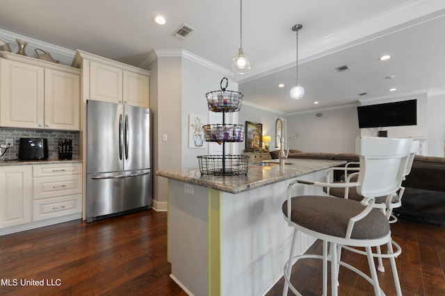 kitchen with light stone counters, visible vents, freestanding refrigerator, and a sink