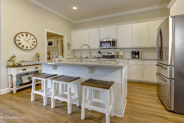 598 Westfield Dr, Pearl, MS 39208 - kitchen with appliances with stainless steel finishes, white cabinetry, crown molding, light stone counters, and a kitchen breakfast bar
