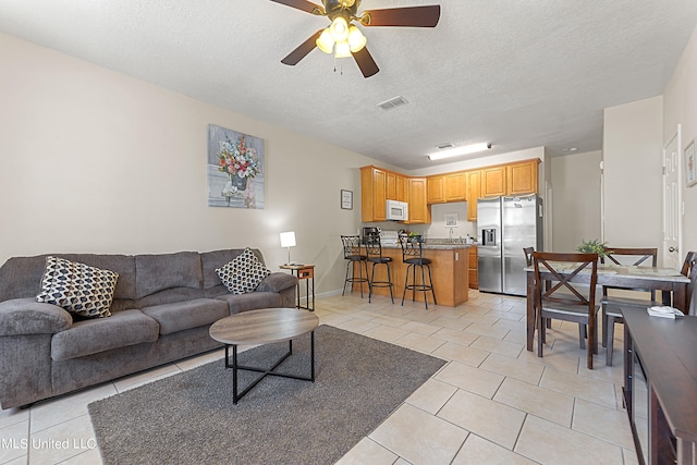 tiled living room with a textured ceiling and ceiling fan