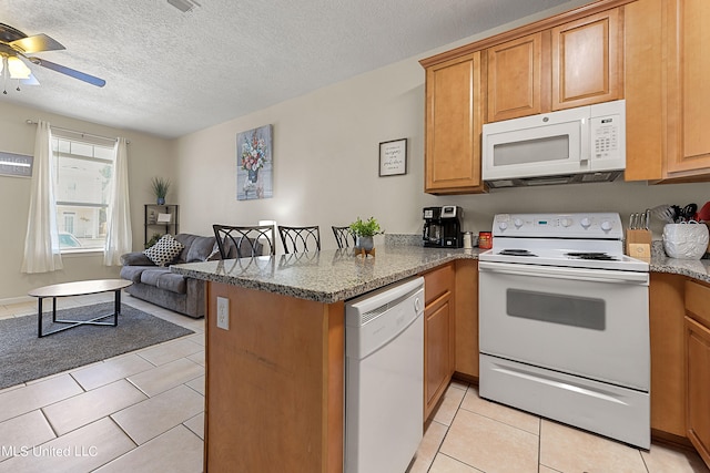 kitchen featuring kitchen peninsula, ceiling fan, a textured ceiling, light tile patterned flooring, and white appliances