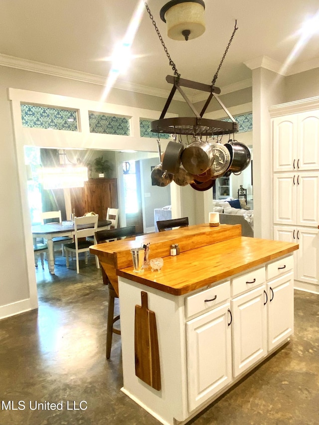 115 Pinedale Rd, Terry, MS 39170 - kitchen with butcher block countertops, crown molding, finished concrete floors, white cabinetry, and a kitchen island